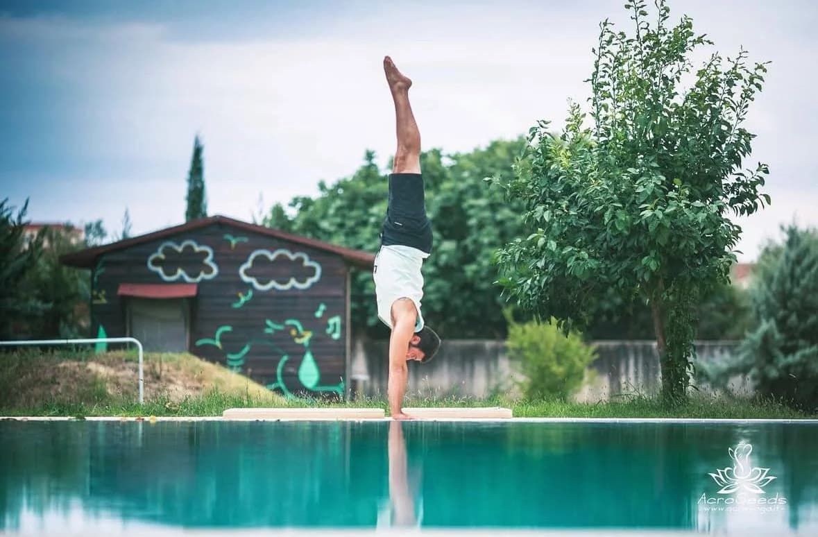 Άνδρας κάνει κατακόρυφο σε εξωτερικό χώρο με φόντο τη φύση.